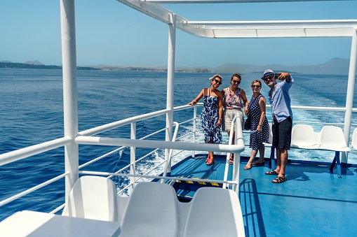 Group of friends on the ferry boat deck on a sunny day traveling on vacation