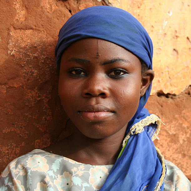 village ,young african girl with a red dress opening the house door