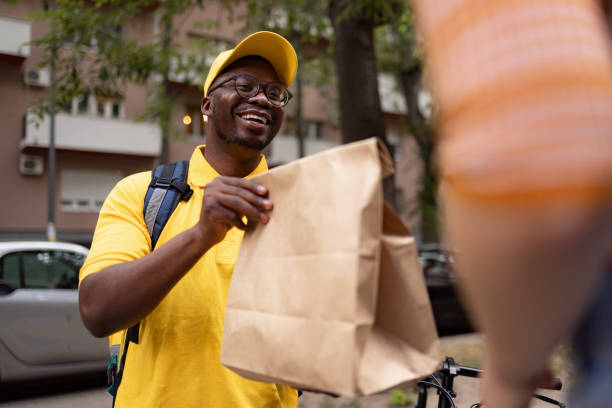 istock Happy black courier delivering a package to his customer. 1571858912