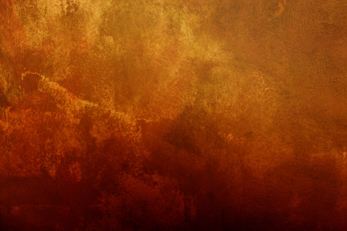 Close up of a brownish rusted welded sheet metal surface with yellowish and orange hue and amber patina.