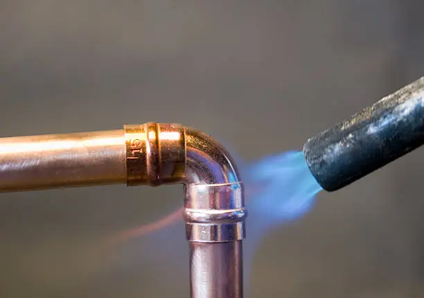 Hot blow torch soldering right angle elbow to 15mm copper tube.