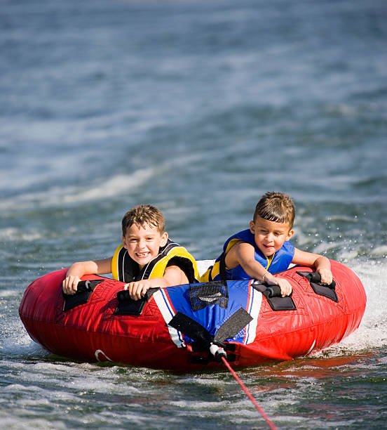 молодые мальчики на лодках - water sport family inner tube sport стоковые фото и изображения