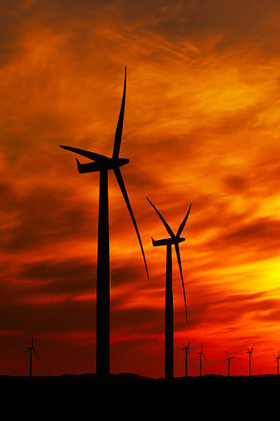 wind turbines against red and orange sunset stock photo
