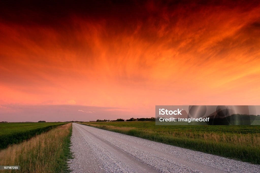 Estrada de cascalho no centro-oeste com dramática do pôr-do-sol - Foto de stock de Manitoba royalty-free