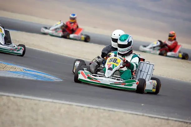 Several modern high speed shifter karts compete at over 100mph on a raceway.