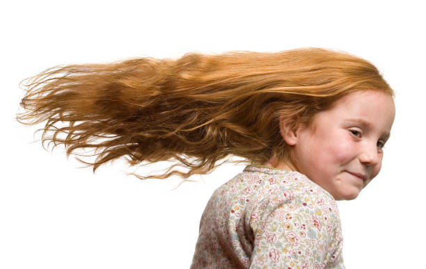 Young girl playing and having fun outdoors with hair blowing in wind
