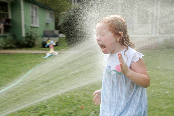 Bath in the yard Girl getting sprayed by a stream of water. hose photos stock pictures, royalty-free photos & images
