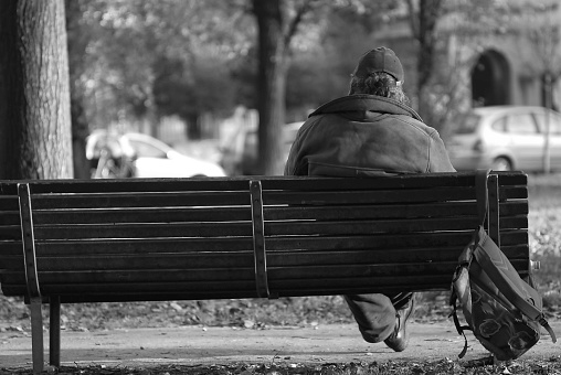 London, United Kingdom – November 10, 2022: A grayscale shot of two men sitting on a bench on a street in London