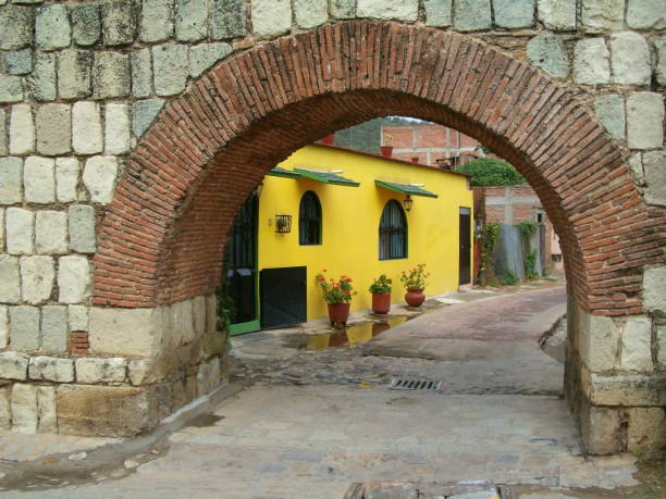 Yellow house behind arch in Oaxaca, Mexico. The wall was built of Oaxaca's tipical vulcanic green stone.