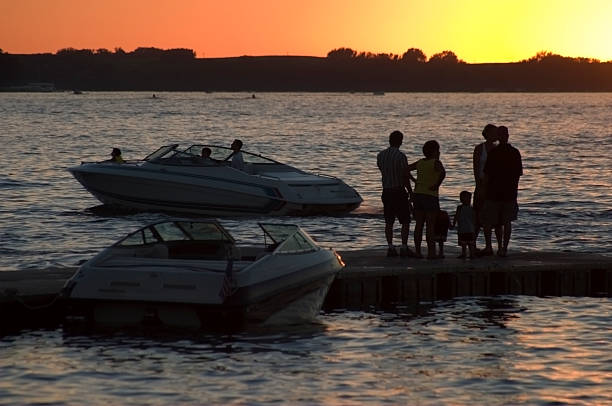 Sunset Action Sunset on West Okoboji Iowa shows boats and people including kids in the foreground, and skiers and jet ski riders in the background. family motorboat stock pictures, royalty-free photos & images