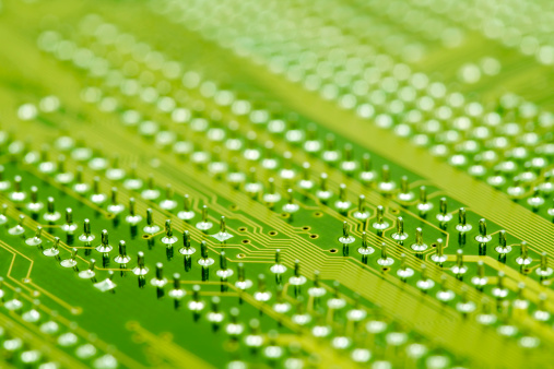 Micro chip and capacitors mounted on a green printed circuit board, close up photo with soft selective focus
