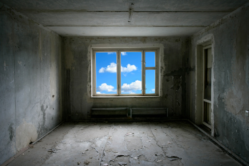 Dark abandoned room with bright blue sky outside the window.