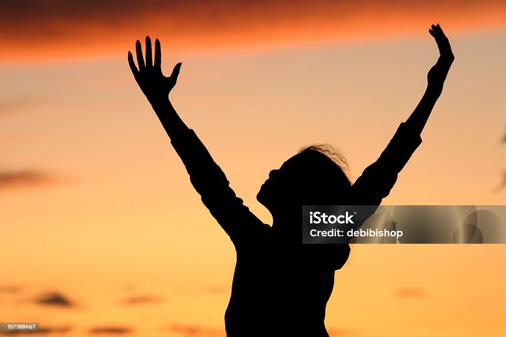 Silhueta de uma garota expressando alegria na hora do nascer ou do pôr-do-sol - Foto de stock de Criança royalty-free