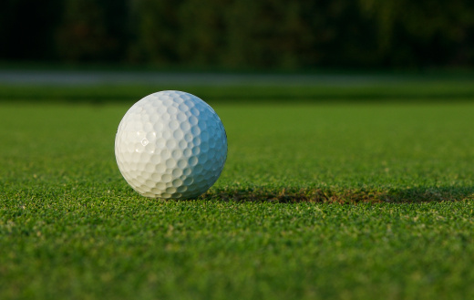 Golf ball on green at the lip of hole