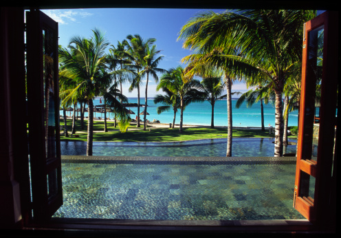 Swimming pool with patterned tiles in a hotel in the Maldives, against the backdrop of a tropical beach.