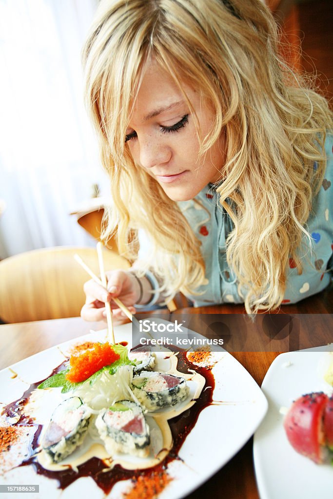 Fille Blonde à la recherche dans une assiette de sushis - Photo de Adulte libre de droits