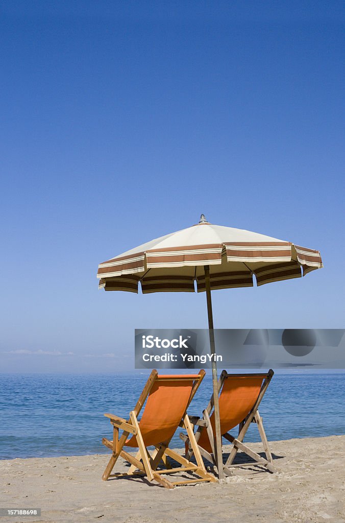 Duas cadeiras de praia e guarda-sol no mar para férias tropicais. - Foto de stock de Azul royalty-free