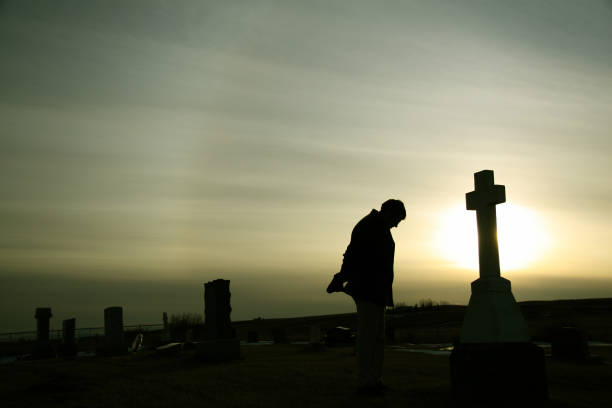 silueta de hombre caucásico de luto en el cementerio - one cross fotografías e imágenes de stock