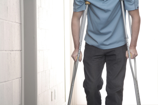 Young man using crutches in hospital.