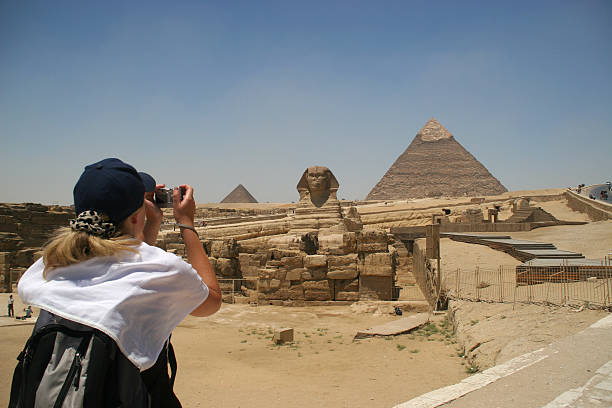 Sightseeing in Giza Blonde female turist takin picture of the Sphinx and the pyramids of Khafre (Chephren) and Menkaur (Mycerinus) in Giza - Cairo, Egypt pyramid giza pyramids close up egypt stock pictures, royalty-free photos & images