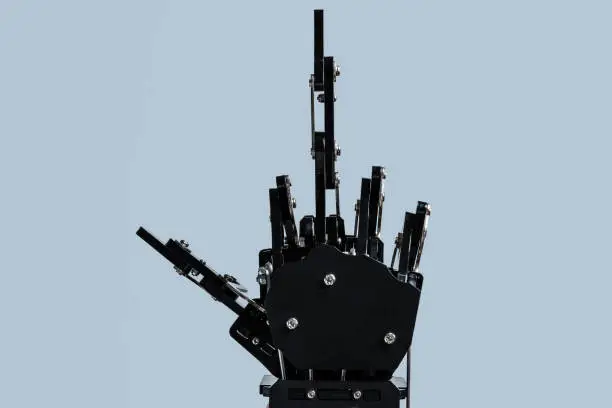 Real robotic hand giving the middle-finger against grey background. Concepts of AI takover and Technological singularity.