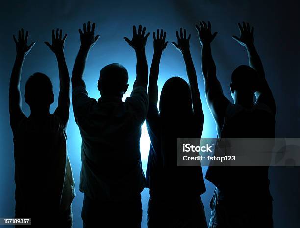Group Of People Silhouette Arms Raised In Praise Blue Light Stock Photo - Download Image Now