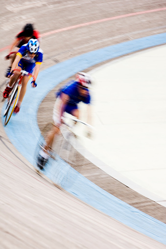 The leading bicycles race round the track. Motion blur on both the cyclists and the track.