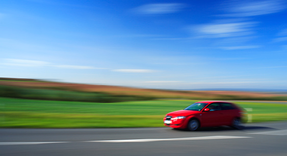 Red Car Speeding, Country Road Through Summer Landscape, intentionally blurred 