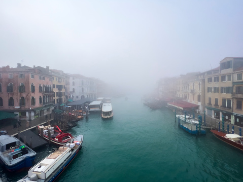 Mist drifts across the famous Grand Canal in Venice. Picturesque view from the Rialto bridge on a winter day. Beautiful high angle shot of Venice, in Italy. Travel destination background with copy space.