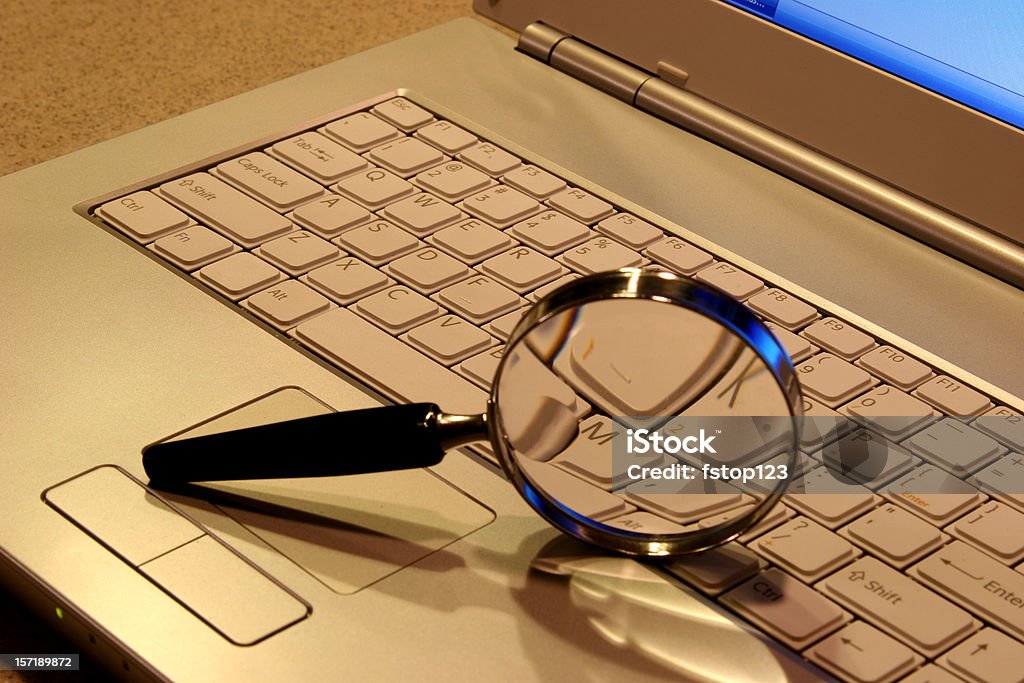 Laptop Computer with magnifying glass on keyboard. Magnifying glass on laptop computer keyboard.  Magnifying Glass Stock Photo
