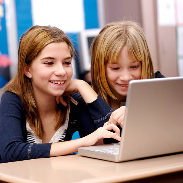 Two kids playing with laptop at school stock photo