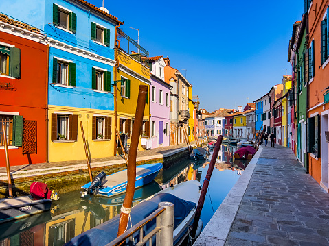Venice, Italy, 01/30/2023; Picturesque colorful canal houses and boats on Burano island in the Venetian Lagoon. A Venice landmark in northern Italy. Beautiful poster like travel and tourism background on a sunny day with copy space.