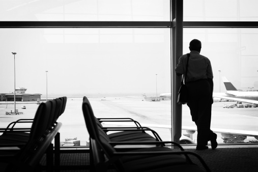 Businessman waiting in the airport lounge by the huge window. Black and white image.