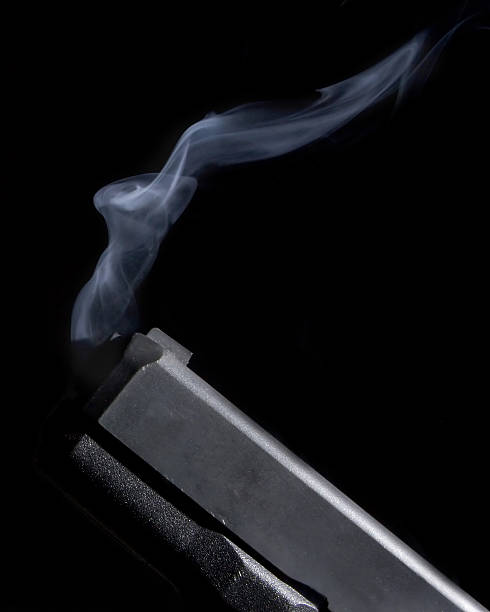 Smoking Gun A close up of a handgun with smoke coming from the end of the barrel.. gun barrel stock pictures, royalty-free photos & images