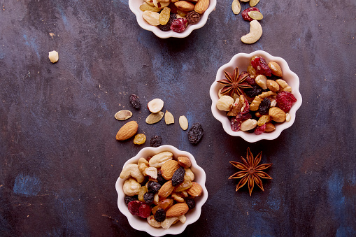 Aesthetic saucers with mixed nuts close up. Walnuts, almonds, hazelnuts, cashew, raisins and cranberries. Healthy food and snacks