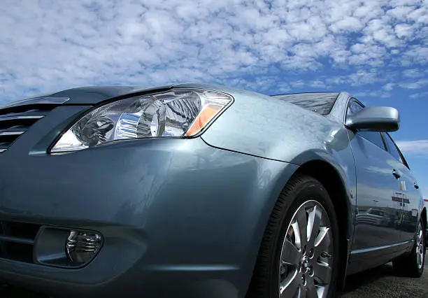 Profile of a shiny, silver sports car on a cloudy day.