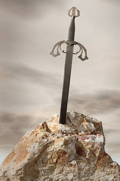 Antique sword stuck in stone rock stock photo
