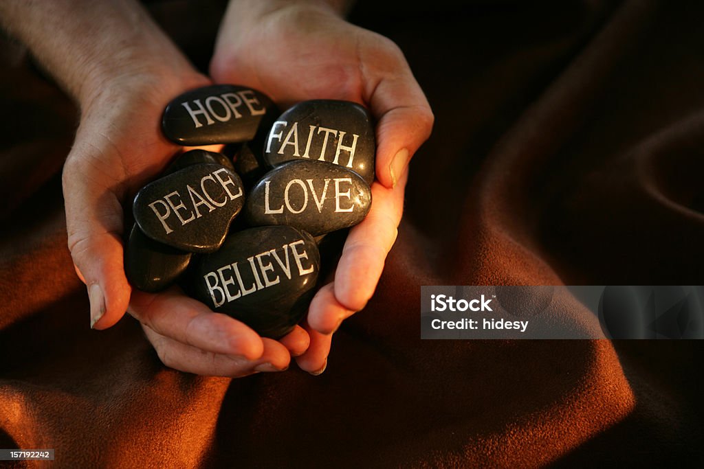 Meditation Hands holding rocks with words on Love - Emotion Stock Photo