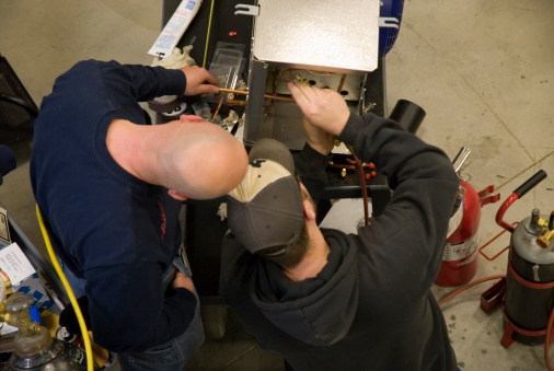 Two students work on sweating a joint during a class in AC installation and  repair
