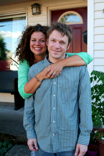 happy young couple in front of first house