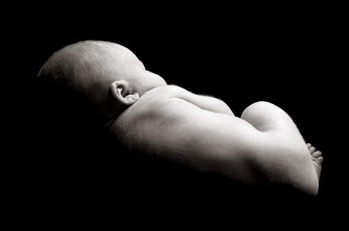 Newborn baby in fetal position isolated on black.  Looks to be in utero.  All around the baby is pure black, so it is very easily expandable in an direction.