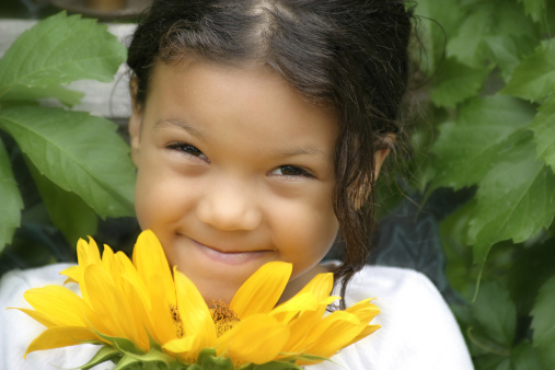 African American girl with a shy smile and a pretty sunflower.