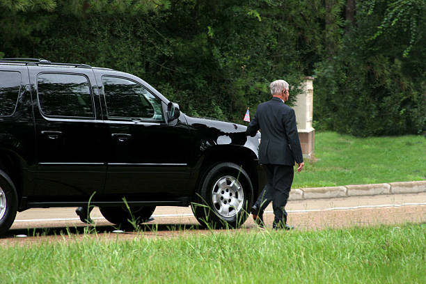 Secret Service men walking beside black SUV. Motorcade. Black SUV with security guards walking alongside.  Motorcade.  government photos stock pictures, royalty-free photos & images