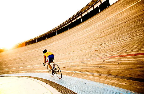 Photo of Cyclist on a velodrome track riding towards the evening sun