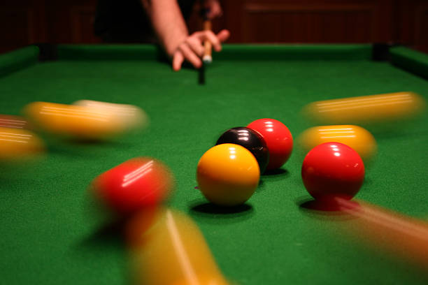 Breaking pool balls Very dynamic picture where we can see in the background the hands of a player who has in hand a cue ball just seconds after breaking pool balls in the foreground during a blackball game. Some balls leave a bright trailed behind them because of the slow-motion. pool ball stock pictures, royalty-free photos & images