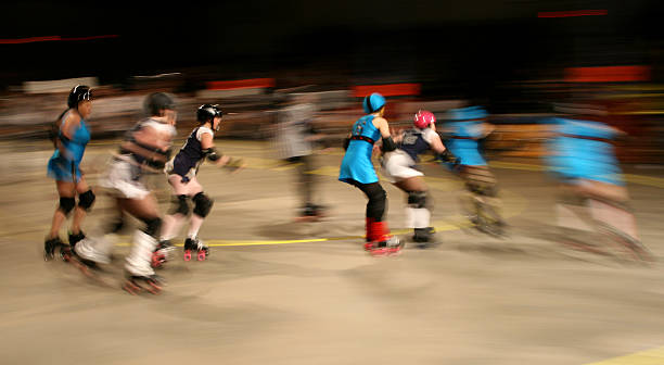 Roller Derby Pack in Motion Girls on roller skates speed by roller rink stock pictures, royalty-free photos & images