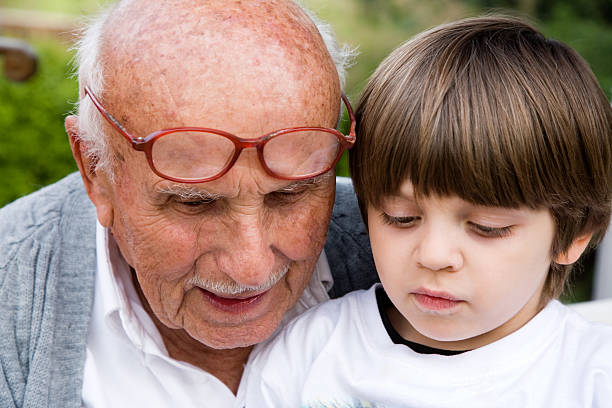 istock Senior man reading  book to child sitting on his lap 157193087