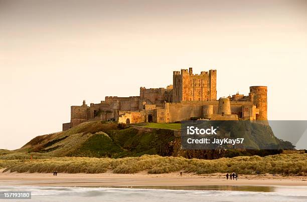 Bamburgh Castle Daytime With People Walking On Beach Stock Photo - Download Image Now