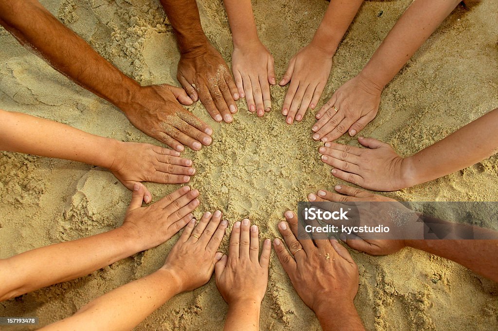 Circle Mandala of 12 Diverse Hands High angle view of a circle of hands touching sand. Horizontal format. Circle Stock Photo