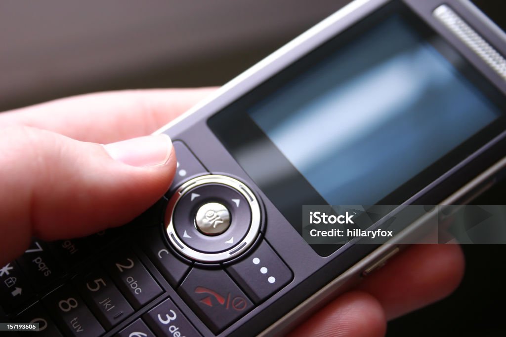 Cell Phone Sleek cell phone in hand with blank blue screen.  Image has a very shallow DOF.  Focus is on finger tip and keys. Blue Stock Photo